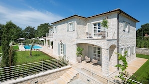 Une maison en pierre à deux étages, dotée d’une piscine, d’un espace extérieur aménagé et d’un jardin bien entretenu.
