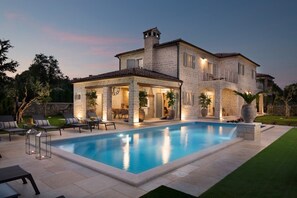 A two-story stone house with a swimming pool, outdoor seating, and a well-lit patio area. - Beautiful Villa with Private Pool (Ladici)