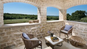 A stone-walled room with two wicker chairs, a small table, and a view of a green landscape. - Beautiful Villa Nevia with Private Pool (Ladici)