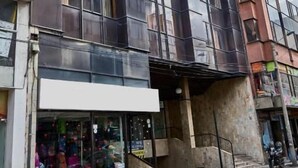 Un edificio de varios pisos con grandes ventanales y una fachada comercial en la planta baja.