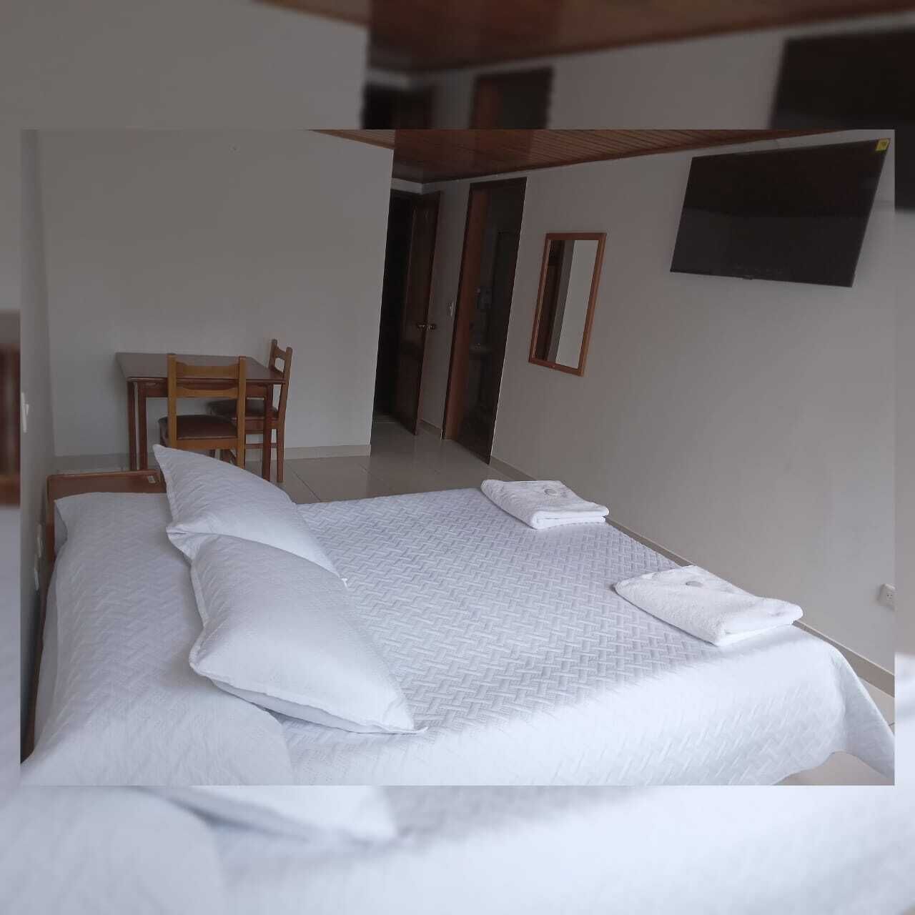 Une chambre à coucher avec un grand lit, une chaise en bois et une petite table.