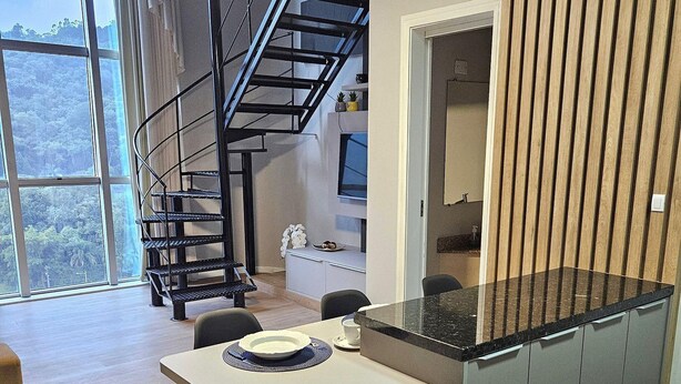 A modern kitchen with a central island, a dining area with two chairs, and a spiral staircase leading to an upper level. - Saint Sebastian Flat 716Duplex no Centro (Jaragua do Sul)