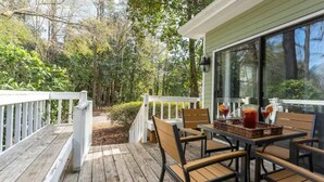A wooden deck with a table and chairs, surrounded by a white railing, overlooking a forested area. - Updated/Resort StyleSleeps-8-Beach-5 min/Pool/Dining/pickle Ball-Prime location (Wilmington)