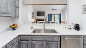 A kitchen with a stainless steel sink, grey cabinets, and a white countertop. - Updated/Resort StyleSleeps-8-Beach-5 min/Pool/Dining/pickle Ball-Prime location (Wilmington)