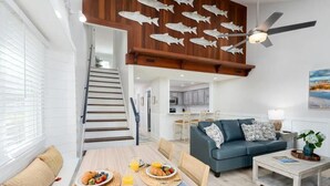 A modern living room with a dining area, a staircase, and a kitchen in the background. - Updated/Resort StyleSleeps-8-Beach-5 min/Pool/Dining/pickle Ball-Prime location (Wilmington)