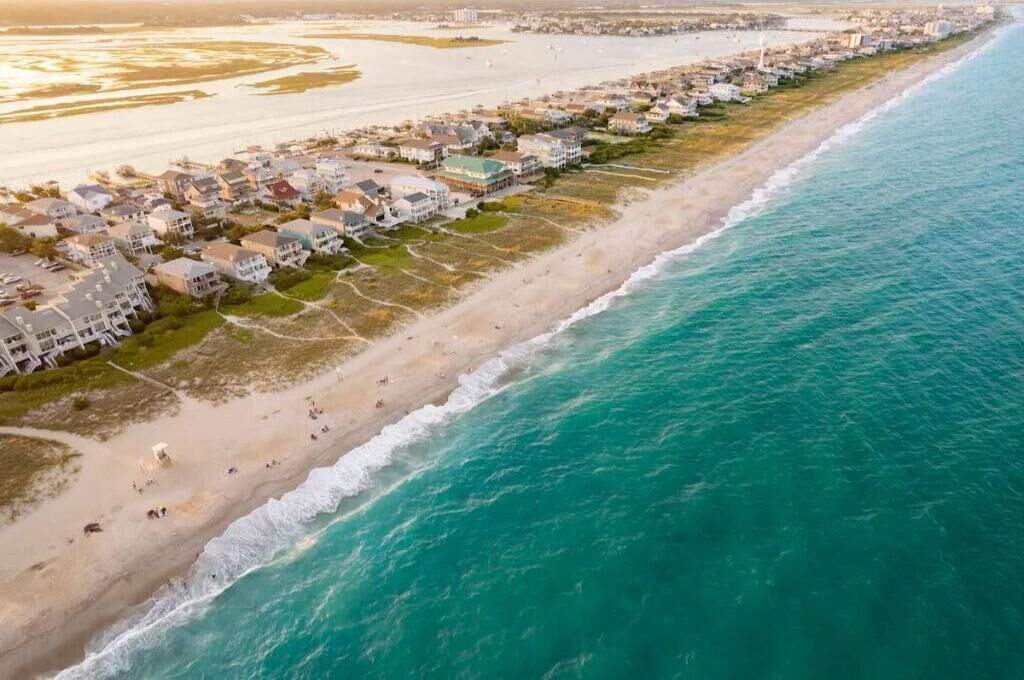 An aerial view of a coastal residential area with houses along the beachfront.