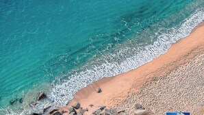 A beach with clear turquoise water, a rocky shoreline, and a sign for Helity real estate. - [Tropea] Luxury Terrace Sea suite ⭐️⭐️⭐️⭐️⭐️ (Tropea)