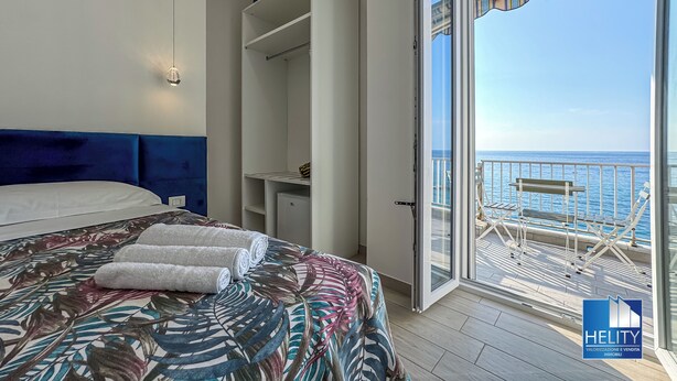 A bedroom with a large bed, a wardrobe, and a balcony with a view of the sea. - [Tropea] Luxury Terrace Sea suite ⭐️⭐️⭐️⭐️⭐️ (Tropea)