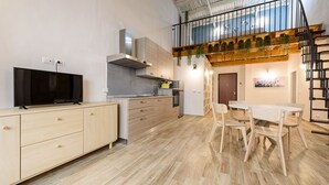 Une cuisine moderne équipée d’un téléviseur à écran plat, de meubles en bois et d’un coin repas avec une table et des chaises.
