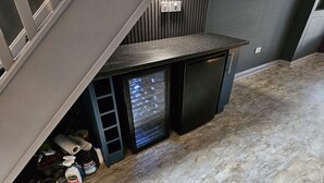 Ein kleiner Küchenbereich mit integriertem Kühlschrank, einer Spüle und einer Arbeitsplatte.