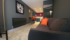 Ein modernes Wohnzimmer mit einem dunklen Sofa, einem Heizkörper und einer Küche im Hintergrund.
