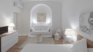 A modern, minimalist bedroom with a white color scheme, featuring a sofa, a bed, a TV, and decorative elements like a lamp and a painting. - Vatican home for seven people  (Rome)