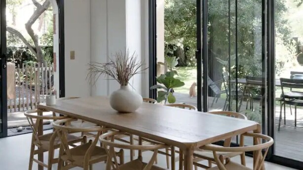 A modern dining area with a wooden table and chairs, a vase, and hanging pendant lights. - Beautiful villa in Pyla, 2 min walk from beach (La Teste-de-Buch)