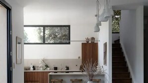 A modern kitchen with wooden cabinets, a dining table, and chairs. A cat is lying on the floor. - Beautiful villa in Pyla, 2 min walk from beach (La Teste-de-Buch)