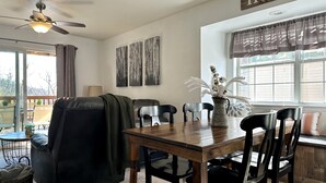 A dining area with a wooden table and chairs, a ceiling fan, and a view of the outdoors. - Hear SDC - Outdoor Pool- Walk to Lake - King Bed (Branson)