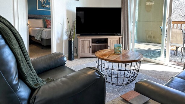 A living room with a leather sofa, a TV, and a coffee table. - Hear SDC - Outdoor Pool- Walk to Lake - King Bed (Branson)