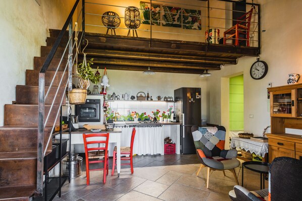 A spacious kitchen with a dining area, a staircase, and a living room with a sofa and a chair. - Casa Balatella con Piscina by Wonderful Italy (Augusta)