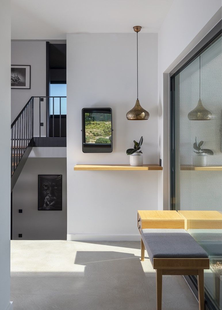 Un intérieur moderne avec un escalier, un banc, une étagère ornée de plantes et une suspension lumineuse.