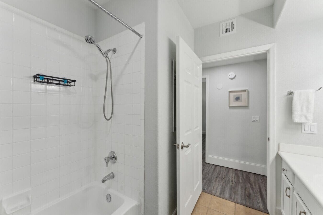 A modern bathroom with a glass-enclosed shower, a bathtub, and a white tiled floor.