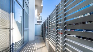 A modern building with a glass facade, a covered outdoor area with a metal fence, and a parking area with cars. - Absolutely spacious APT unit between ANU and City (Canberra)