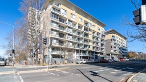 A multi-story residential building with balconies, a parking lot, and a clear blue sky. - Absolutely spacious APT unit between ANU and City (Canberra)
