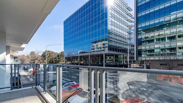 A modern building with a glass facade, a parking area with cars, and a clear sky. - Absolutely spacious APT unit between ANU and City (Canberra)