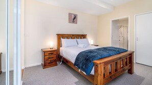 A bedroom with a wooden bed, bedside tables, a wardrobe, and a shower area. - Absolutely spacious APT unit between ANU and City (Canberra)