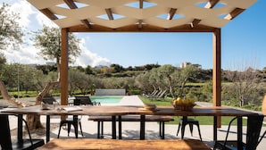 Una pérgola de madera con piscina y zona de estar al aire libre.