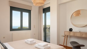 Un dormitorio con cama, escritorio, silla, espejo redondo y vistas al exterior.