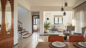 Una sala moderna con una mesa de comedor de madera, sillas naranjas y una escalera que sube a otro nivel.