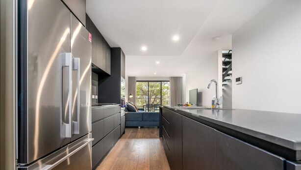 A modern kitchen with stainless steel appliances, a wooden floor, and a view of the outdoors. - Contemporary Tri-Level APT in a Prime Central Spot (Braddon)