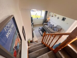 Una escalera conduce a una sala de estar con un sofá, una mesa de centro y un televisor.