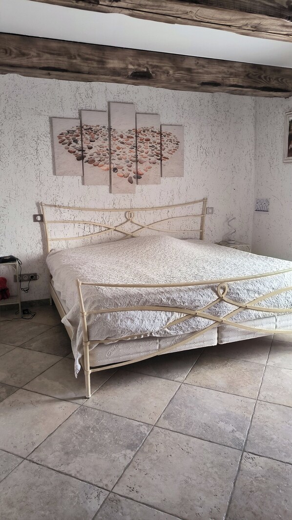 A bedroom with a bed, a wall-mounted artwork, and a tiled floor. - House at the foot of the Luberon with swimming pool 5 minutes from the village of Lourmarin, (Puyvert)