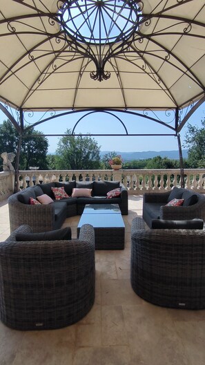 An outdoor seating area with wicker furniture, a central table, and a decorative ceiling. - House at the foot of the Luberon with swimming pool 5 minutes from the village of Lourmarin, (Puyvert)