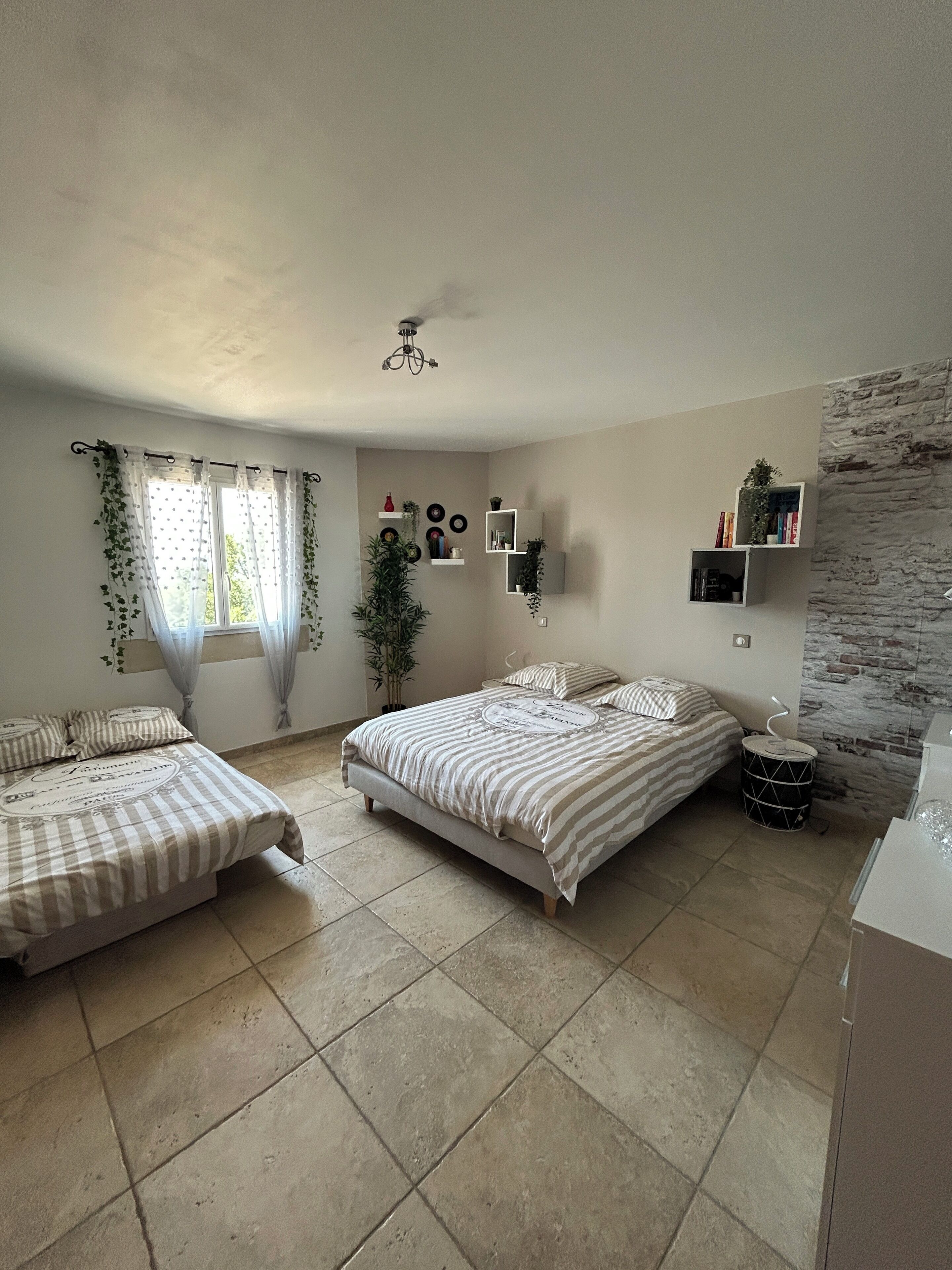 A bedroom with two beds, a ceiling fan, and a brick accent wall.