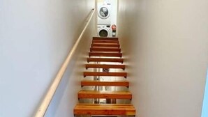 A narrow staircase with wooden steps leading to a laundry room. - Bootlegger’s Nest
 (Anchorage)