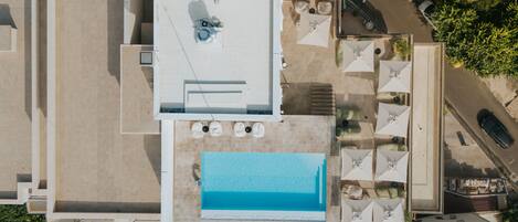 Vue aérienne d’un toit-terrasse avec une piscine, un espace salon extérieur et un parking.