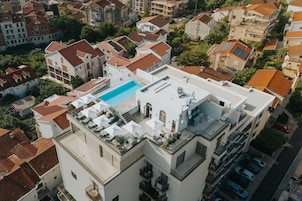Un edificio residencial con piscina en la azotea, varios balcones y vista a la calle.