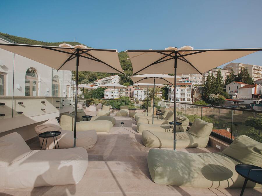 Terraza en la azotea con mobiliario exterior, incluyendo sofás y sillones, y grandes sombrillas que ofrecen sombra.