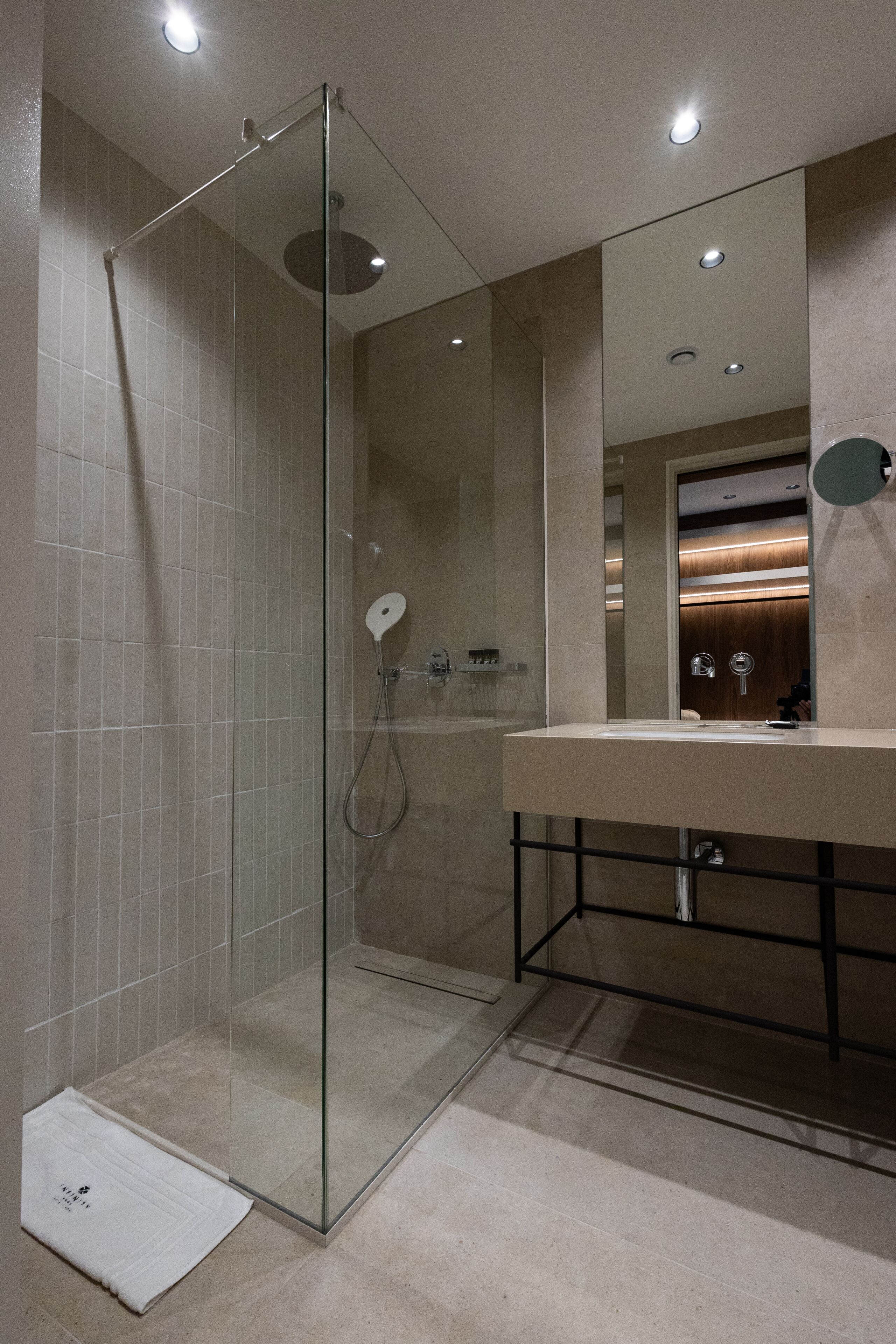 A modern bathroom with a glass-enclosed shower, a vanity with a mirror, and recessed lighting.