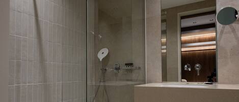 A modern bathroom with a glass-enclosed shower, a vanity with a mirror, and recessed lighting.
