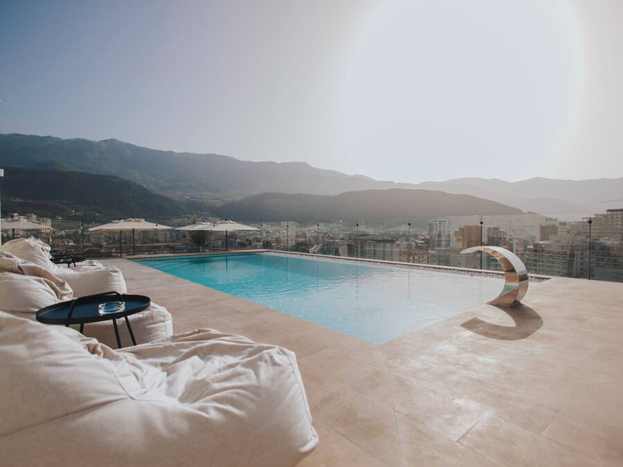 A rooftop pool with a view of mountains and cityscape.