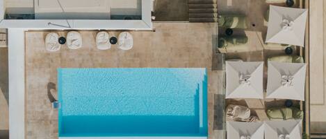 An aerial view of a hotel with a swimming pool surrounded by sun loungers and umbrellas.