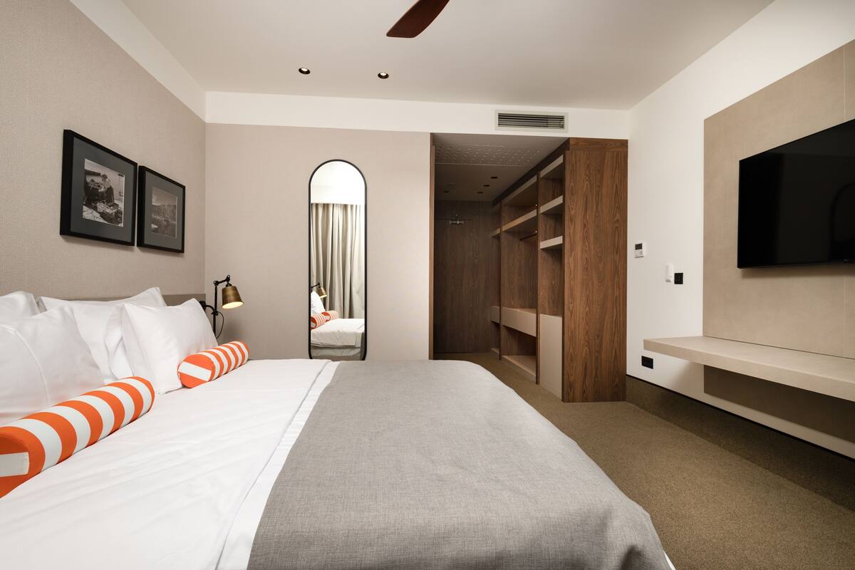 A hotel room with a bed, a TV, a wardrobe, and a mirror.