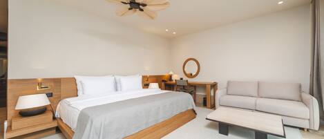 Una habitación de hotel moderna con una cama grande, un escritorio, un sofá y un ventilador de techo.