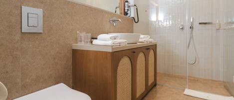 Un baño moderno con inodoro, lavamanos y ducha.