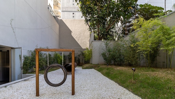 A courtyard with a tire swing, gravel ground, and a building in the background.