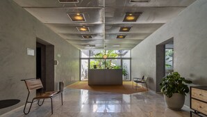 En rummelig lobby med en marmorgulv, et centralt siddeområde og en stor potteplante.