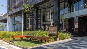 Un edificio moderno con fachada de vidrio, un banco de madera y un letrero que dice "BE URBAN".