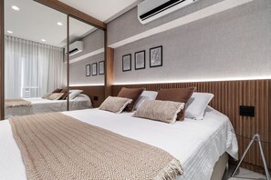 A modern hotel room with a large bed, a mirror, and framed pictures on the wall. - Studio next to Congonhas (São Paulo)